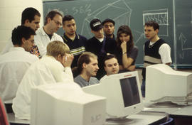 Photograph of students gathered around the computers in the lab