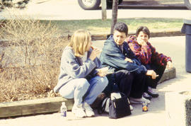 Photograph of students sitting on the curb