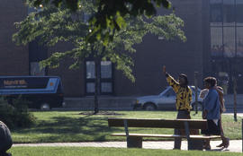 Photograph of a person waving while walking to the entrance of IE building