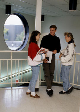 Photograph of students in conversation near a stairway landing
