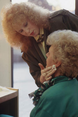 Photograph of student applying makeup to a client in the makeup studio
