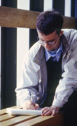 Photograph of a student using the hall bench by the windows as a substitute table