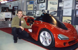Photograph of a student posed with a model car
