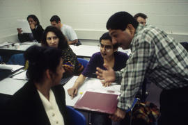 Photograph of students having a discussion with an instructor in a COBOL programming class