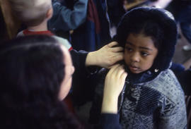 Photograph of toddler being dressed in a winter coat