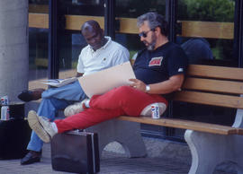 Photograph of two students seated on a bench reviewing notes