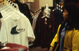 A photograph of a student browsing for shirts in the bookstore