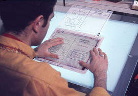 Photograph of a student viewing a drafting diagram on a light tabel in the lab