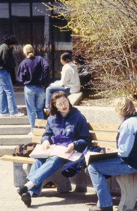 A photograph of two students working while seated on a bench