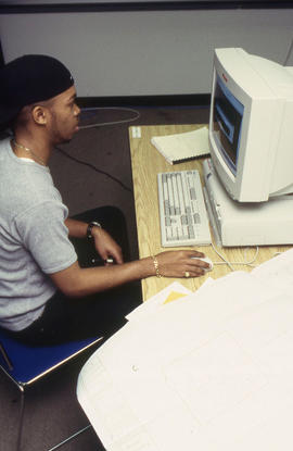 A photograph of a student sitting at a computer in the Technology lab