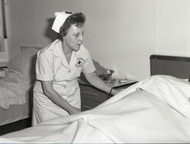 Photograph of a nurse making the bed