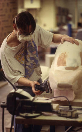 A photograph of an Industrial Design student sanding down their model