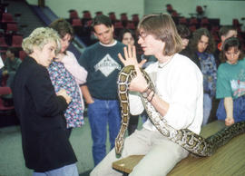 Photograph of a reptile handler answering questions while holding an anaconda
