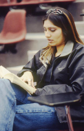 Photograph of a student sitting in the Lecture Theatre and reading a book