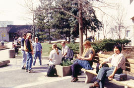 Photograph of students seated on benches in the courtyard