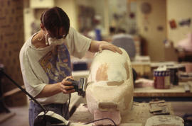 A photograph of an Industrial Design student sanding their design model