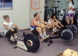 Photograph of three staff members on rowing machines