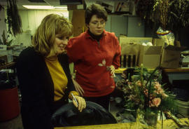A faculty member examines their student's floral creation