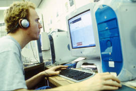 A photograph of a student in headphones working on a computer