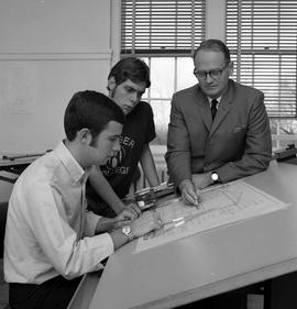 Photograph of an Architectural instructor explaining drafting to two students