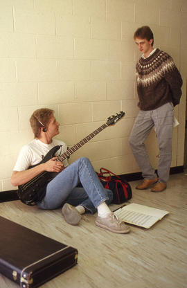 Photograph of a musician with his instrument speaking with another person