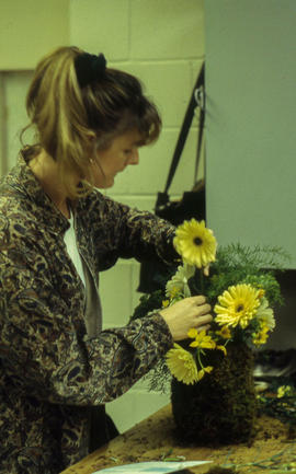 A photograph of a Retail Floriculture student building an arrangement