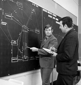 Photograph of Bill Pitt explaining the elements of a work flow schematic to a student