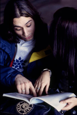 A photograph of two students pouring over a book