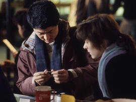 Photograph of two unknown persons examining an object
