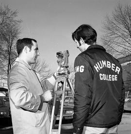 Photograph of an instructor explaining the use of survey equipment to a student