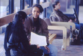 A photograph of students sitting on benches in a hallway