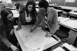 Photograph of an Interior Design Faculty Member Working wtih Students at a Drafting Table