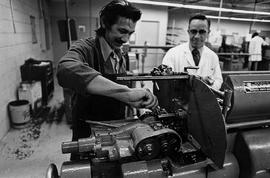 Photograph of Ernie Horney Watching a Student Use Mechanical Equipment
