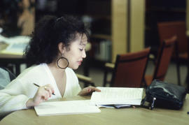 Photograph of a student writing notes from a book in the Learning Resource Centre