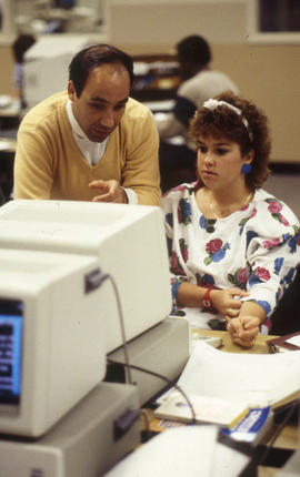 Photograph of an instructor helping a student in personal computer lab