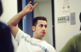 A photograph of a student in class with a raised hand