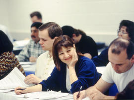 A photograph of a student in lecture smiling at her peer