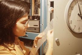Staff member using a machine for grading multiple choice tests : [photograph]
