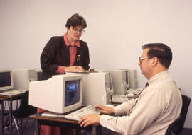 Photograph of an instructor and their student in the computer lab