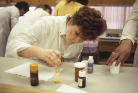Photograph of a student working with containers in a pharmacology lab