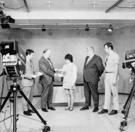 Photograph of Gordon Wragg being filmed presenting awards to various students