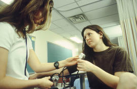 Photograph of nursing students learning to use a stethoscope and blood pressure cuff in the lab
