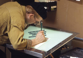 Photograph of a Photography student inspecting negatives on lightbox