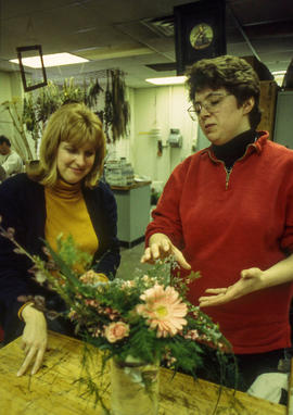 A photograph of an instructor examining a floral arrangement