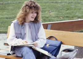 Photograph of a student sitting on an outdoor bench