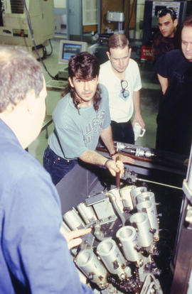 Photograph of students making adjustments to a complex piece of equipment in the Mechanical Engin...