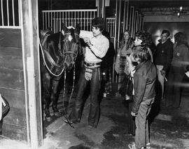 Photograph of a Student Stable Boy Fixing the Bridal on a Horse during Open House