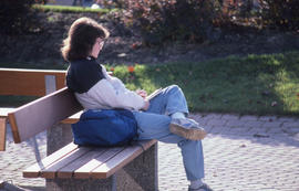 Photograph of a student writing notes while sitting on a bench