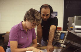 Photograph of instructor and student working at electronics workbench