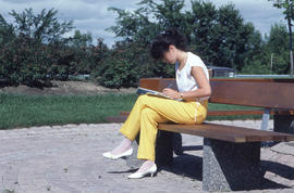 Photograph of a student studying on a bench outside